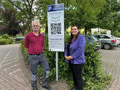 Bargeldlos bezahlen: Jennifer Westendorf und Frank Lumplesch vor der neuen Beschilderung zum Start des neuen Parkraumbewirtschaftungssystems.